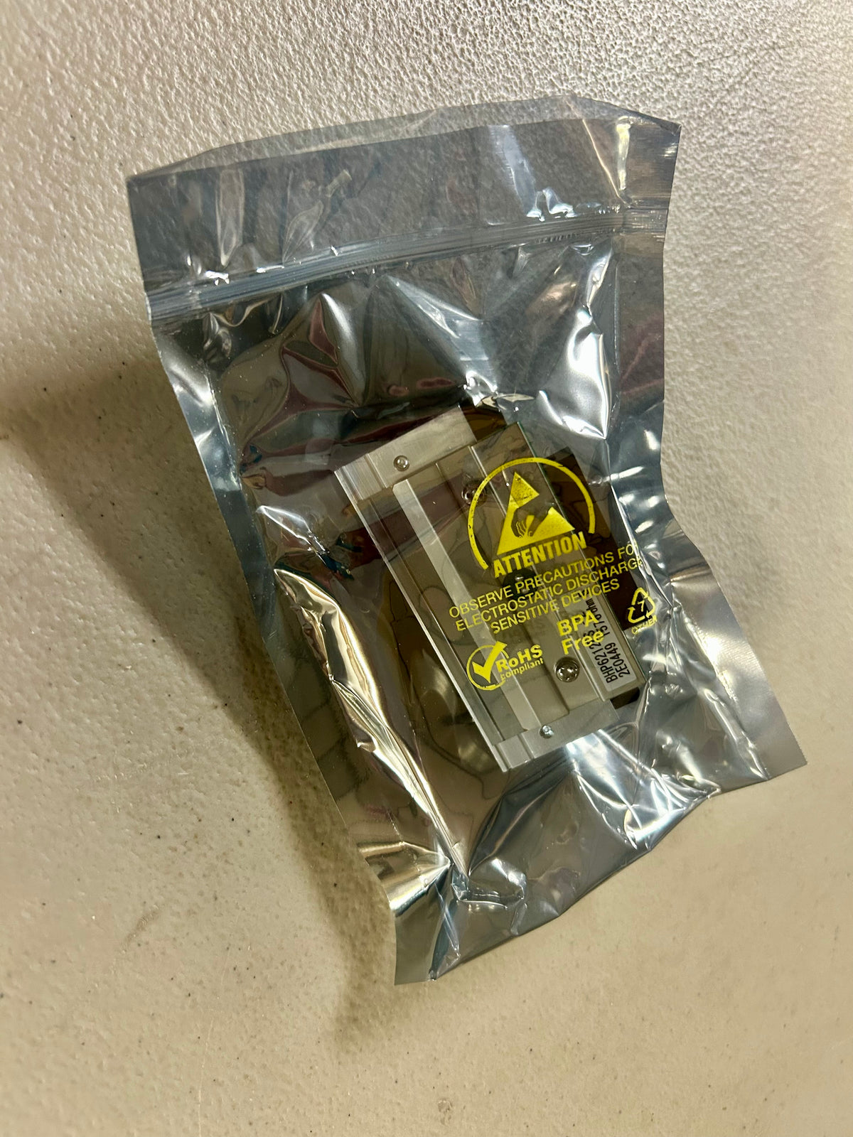 Small electronic component in a clear plastic bag on a beige surface